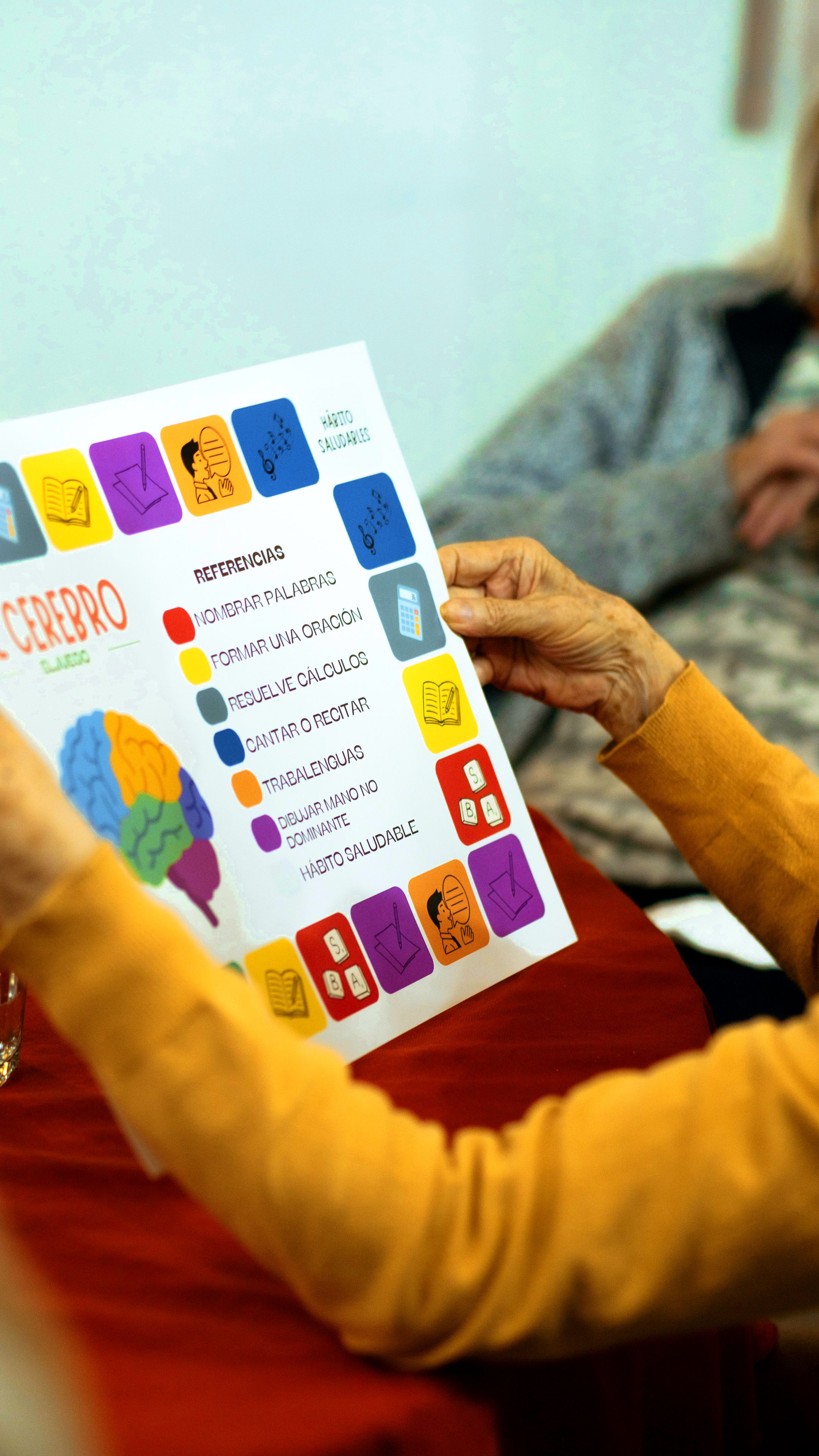 Manos de una residente sosteniendo una ficha del taller de memoria
